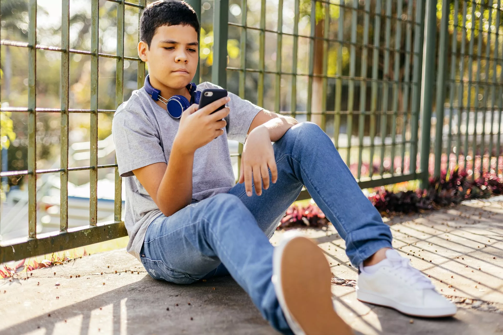 Menino sozinho olhando para o celular, provavelmente ansioso